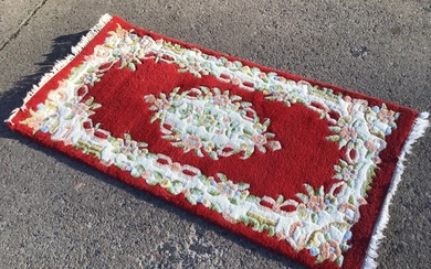 An Indian aubusson style rug with floral medallion on red...