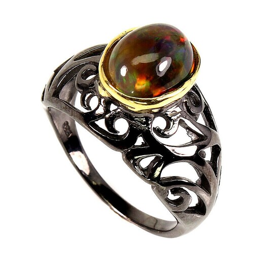 An opal ring set with a cabochon opal, mounted in black rhodium plated sterling silver. Size 56.