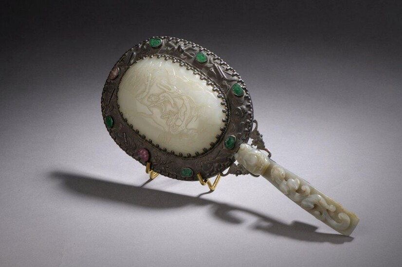 MIRROR of the face to hand type composed of a handle formed by a celadon jade-nephrite fibula carved in high relief with a qilong dragon and its cub, the head forming a hook; the back of the mirror decorated with a ruyi scepter plate in celadon...