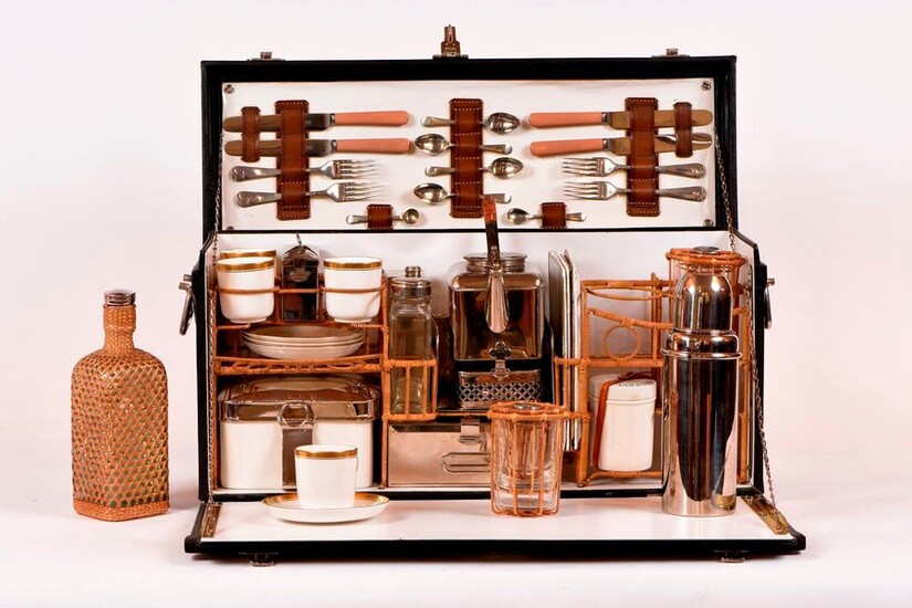 Picnic kit for 4 people. Trunk sheathed in black leather, metal handles, clasps and locks, opening on an interior including 4 forks, 4 knives (goldsmith Maleham & Yeomans), 4 dessert spoons, 1 teaspoon, 1 small salt spoon, 4 rectangular enamelled...