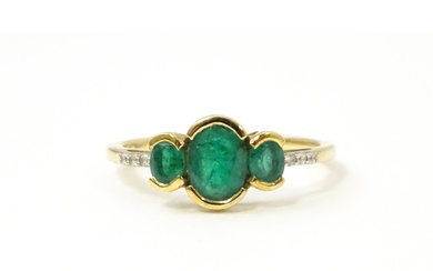 A 9ct gold ring set with three emeralds flanked by white sto...