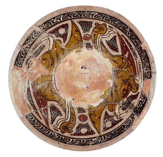 A pottery bowl, Central Asia, 19th century, slip-painted with two addorsed birds in green, black abstract panels with white and red spots to interstices, the central well with damage to glaze, 20.5cm. diam.