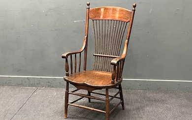An Arts & Crafts oak stick back armchair, the high back over an elm saddle shaped seat on turned