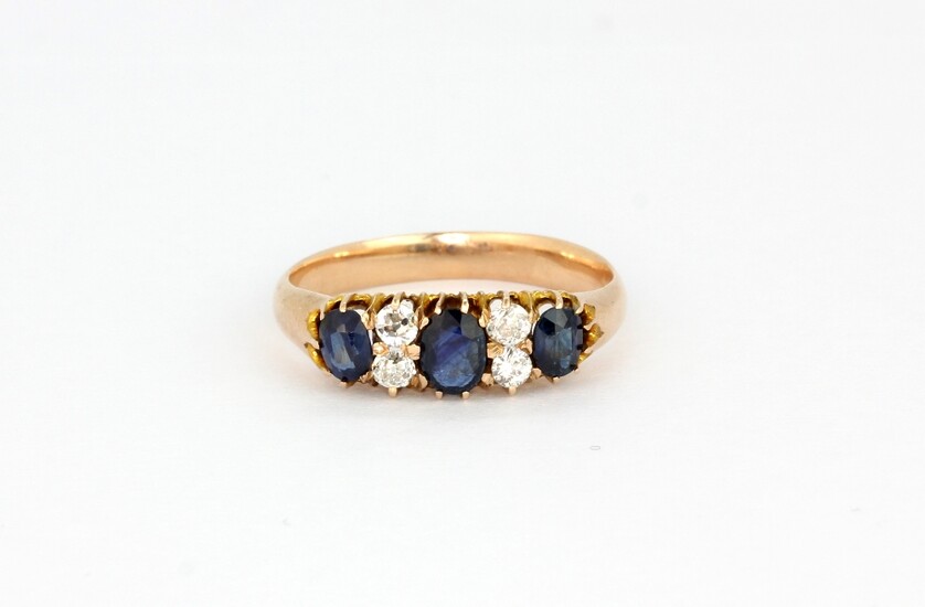 An antique yellow metal (tested high carat gold) ring set with oval cut sapphires and brilliant cut diamonds, (N).