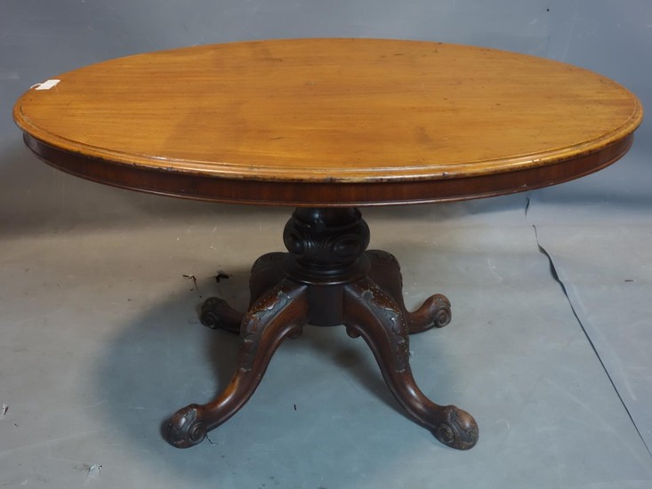 An oval mahogany dining table, on turned support and scrolli...