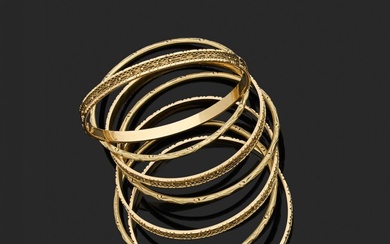 Bracelet semainier en or jaune 18K composé de sept bracelets rigides, certains à décor de...