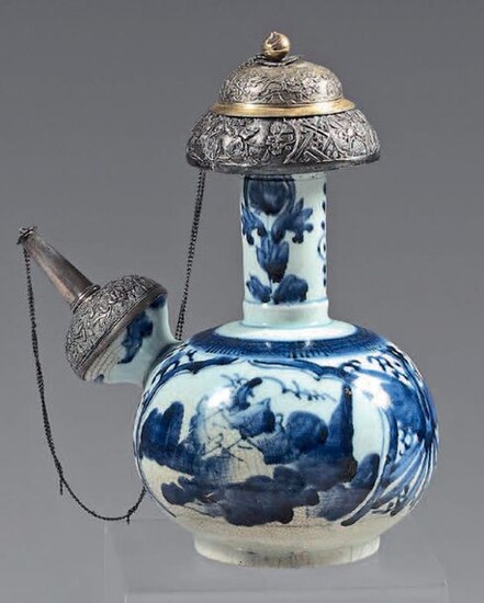 Kendi in Japanese porcelain with silver and silver-gilt frames. 17th century porcelain, silver 900°/°° silver mounts, foreign work. With blue-white decoration of landscapes in reserves, flowers on the neck, cracks, craquelures.