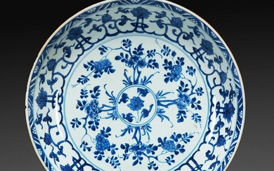PLAT À PAROI ARRONDIE en porcelaine blanc bleu, à décor floral concentrique. Marque au lingzhi dans un double-cercle. (Un éclat...
