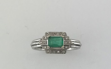Platinum ring set with an emerald in a...
