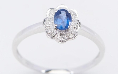 A SAPPHIRE AND DIAMOND CLUSTER RING IN 18CT WHITE GOLD, CENTRALLY SET WITH AN OVAL CUT BLUE SAPPHIRE WEIGHING 0.70CT, WITHIN A DIAMO...