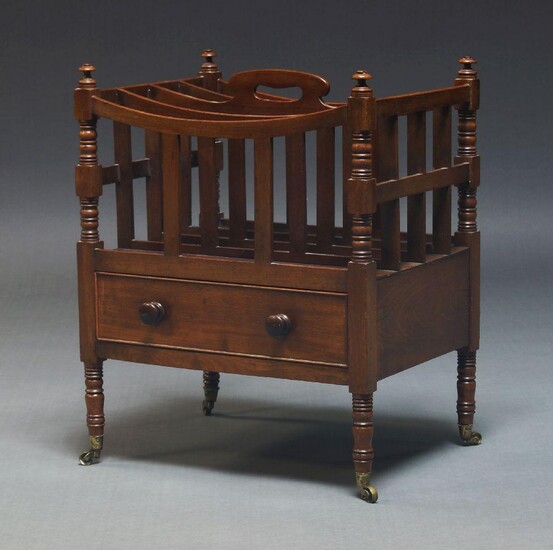 A Victorian mahogany Canterbury, with four divisions and pierced handle, having drawer to base, on turned legs with brass caps and castors, 59cm high, 47cm wide, 35.5cm deep