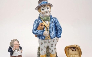 A large Staffordshire character jug, 19th century, modelled as a gentleman in blue pinstripe jacket and floral print decorated trousers with cane under his arm, seated upon a grassy knowle, 34.5cm high, together with a Staffordshire figure of a...