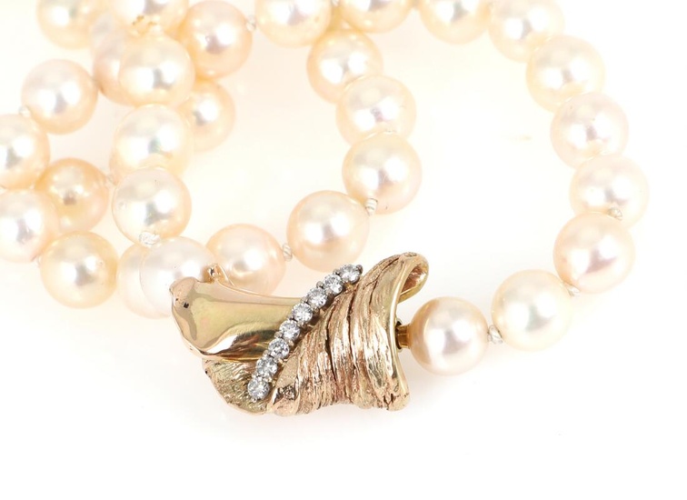 A pearl necklace set with numerous Akoya cultured pearls and a diamond...