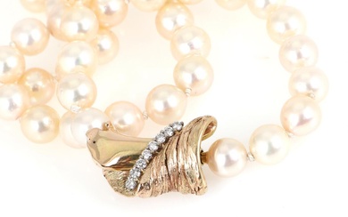 A pearl necklace set with numerous Akoya cultured pearls and a diamond...