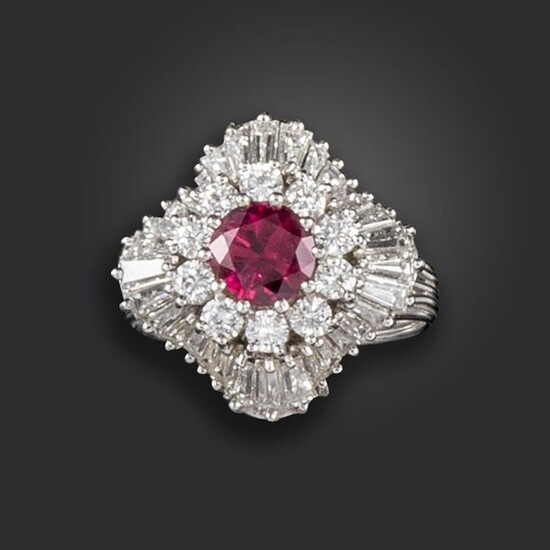 A ruby and diamond cluster ring, the circular-cut ruby set within a surround of circular-cut diamonds and further border of undulating tapered baguette-shaped diamonds in platinum, size O