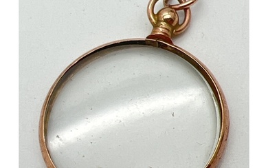 A vintage 9ct rose gold framed glass locket with hanging bal...