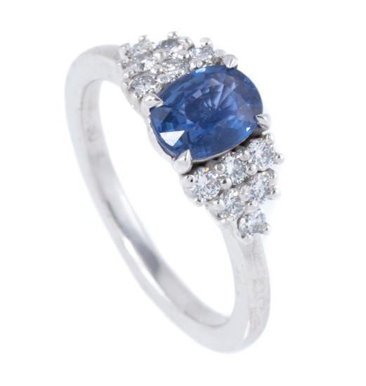 AN 18CT WHITE GOLD SAPPHIRE AND DIAMOND RING; centring a 1.24ct fine blue oval Ceylon sapphire between shoulders set with 12 round b...