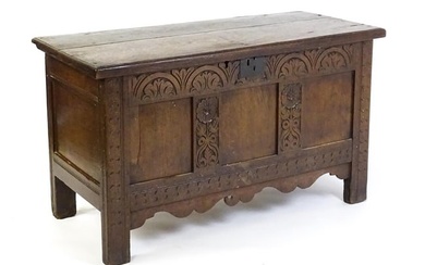 An early 18thC oak coffer of peg jointed construction, with a hinged lid and a carved, panelled
