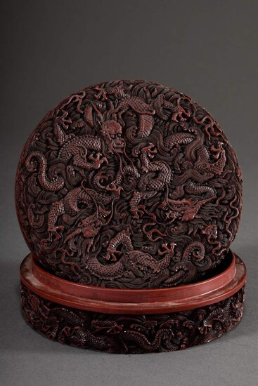 Round red lacquer lidded box "Nine Dragons" in detailed, very fine workmanship, titled on the lid, bottom with Qianlong mark, China early 20th century, h. 6,5cm, Ø 16cm, inside hairline cracks, outer wall with cracks