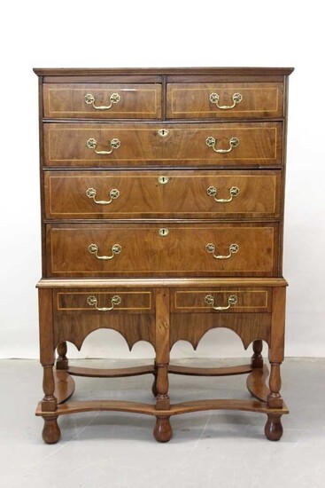 18th century and later walnut chest on stand with two short and three long graduated drawers and two drawers below with brass handles, crossbanded and feather strung decoration on turned legs joine...