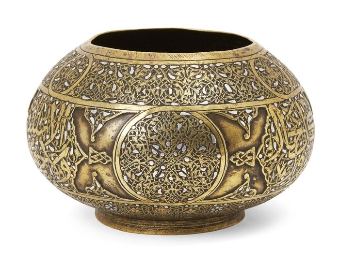 A Cairoware silver inlaid brass bowl, Egypt or Syria, 19th century, on a short foot, decorated with a band to body containing roundels and strapwork and Arabic inscriptions on a dense ground of scrolling vine, 16.3cm. diam.