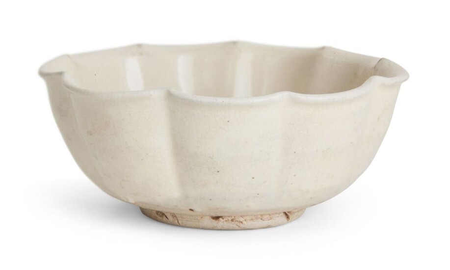 A Chinese stoneware white-glazed foliate bowl, Song dynasty, on short foot with lobed sides that rise to a foliate rim, covered in an allover white glaze of ivory tone than falls just short of the foot, 11.6cm wide