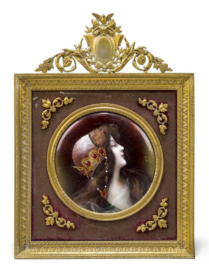 A French enamel portrait plaque of a maiden, early 20th century, depicted wearing a jewelled cap, gilt monogram, in a gilt-brass frame surmounted by a vacant cartouche, the plaque - 7.8cm diameter, 18.2cm high overall