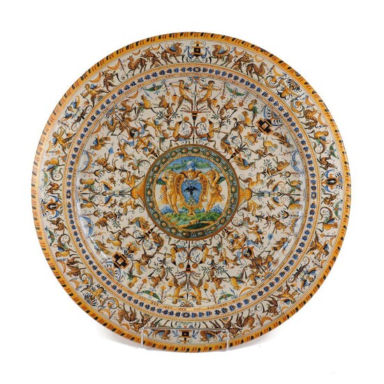 A Italian maiolica armorial charger, late 19th century, in the late 16th century Urbino style, decorated overall with animals, cherubs and grotesques around a central reserve painted with cherubs flanking an heraldic shield, 51cm diameter