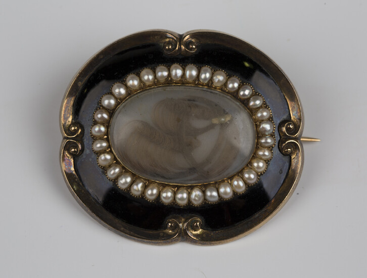 A Victorian black enamelled and half-pearl set shaped oval mourning brooch, glazed with an oval hair