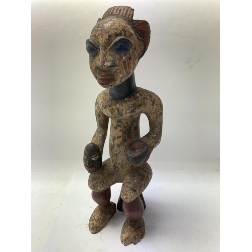 A carved and painted west African tribal figure of a seated ...