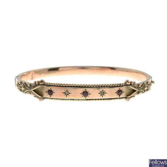A late Victorian 9ct gold diamond and red gem hinged bangle.