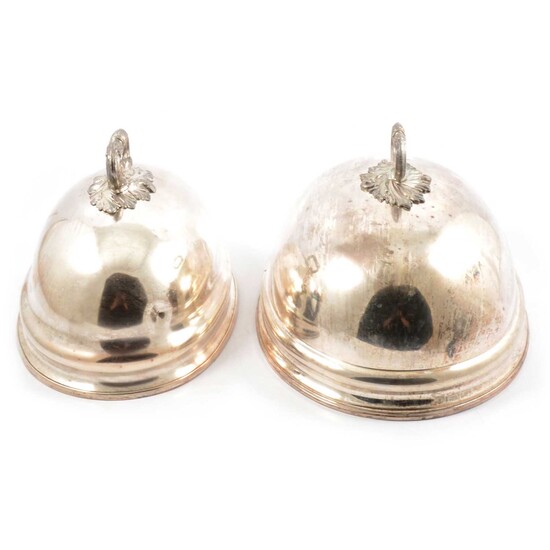 A pair of matching silver-plated meat covers, one slightly larger than other.