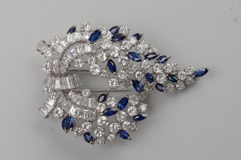 An 18 karat white gold brooch set with brilliant-cut diamonds and baguette-cut diamonds for a total of +/-15 carats and marquise cut sapphires for a total of +/-2.75 carats. Total weight:+/-23.55grs.