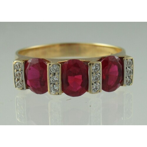An 18ct gold three stone ruby and diamond ring. The three ov...