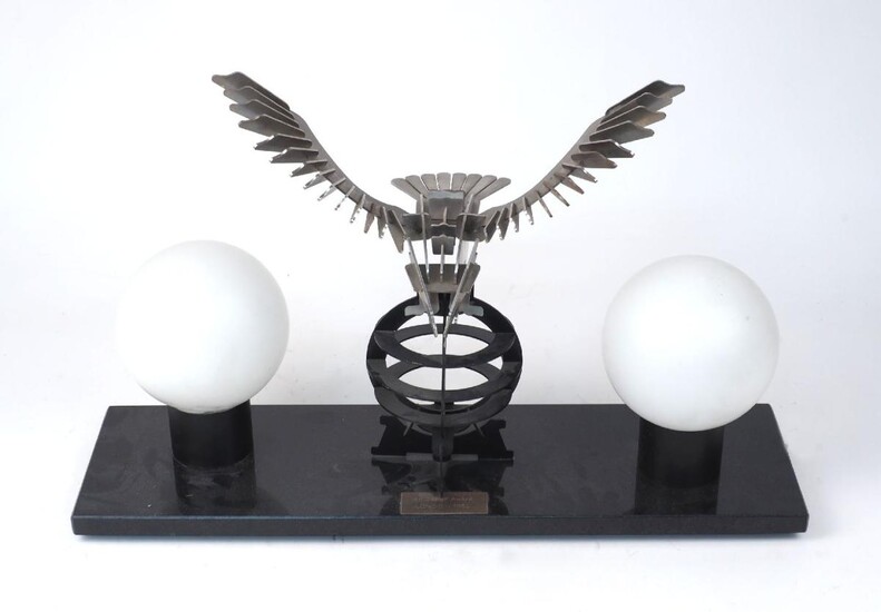 An Art Deco style table lamp, with metal eagle on pierced globe to centre flanked by opaque glass globe shades on a rectangular marble base, bearing plaque engraved 'Art Design Award, London 1930', approx. 37cm high, 60cm wide, 17cm deep It is the...