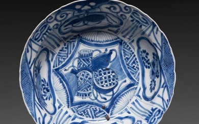COUPE À AILE POLYLOBÉE en porcelaine et émail bleu sous couvert, à décor de style kraak, représentant des rouleaux et des fruit...