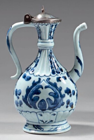 Chinese porcelain ewer with silver frames. Kangxi porcelain (1662-1722), silver frames 800°/°°° posterior, foreign work. Flattened ovoid shape with shoulder, gadrooned neck and base, with blue-white decoration of palmettes, stylized flowers and leaves...