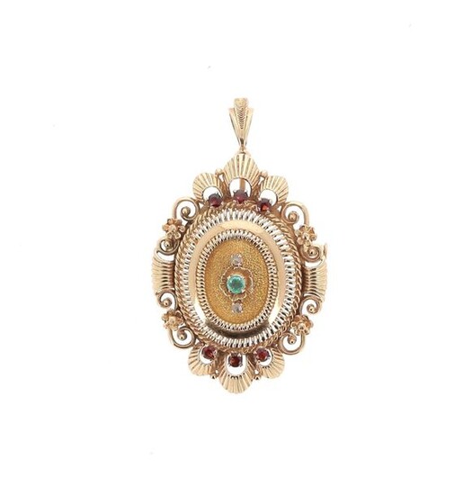 Oval brooch or pendant in 18 K(750°/°°) yellow gold with chased and stamped decoration presenting openwork volutes. In the center, an emerald surrounded by two faceted diamond chips, on each side, three brown-red garnets.