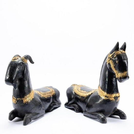 TWO INDIAN CARVED BLACK & GILT RECUMBENT ANIMALS