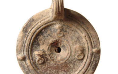 A Roman ceramic discus lamp with theater masks