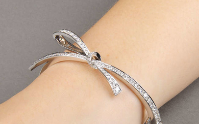 An 18ct gold diamond bow motif hinged bangle.