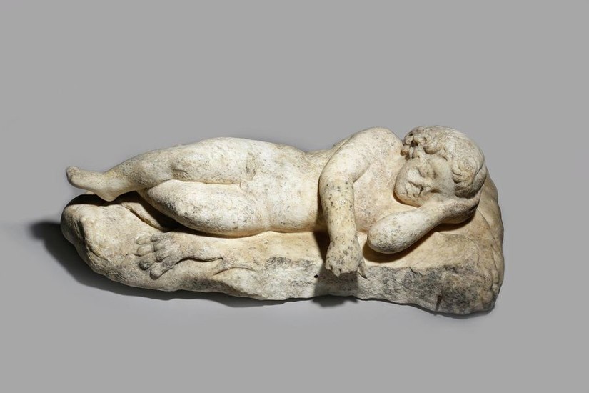 A CARVED MARBLE FIGURE OF EROS SLEEPING lying...