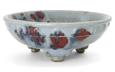 A Chinese imitation-Junyao 'narcissus' bowl, Qing Dynasty, the stoneware body covered overall in a pale blue glaze splashed in purple, standing on three cloud feet and decorated with bosses under the rim, impressed 'shan' mark to base, 17cm diam. 清...