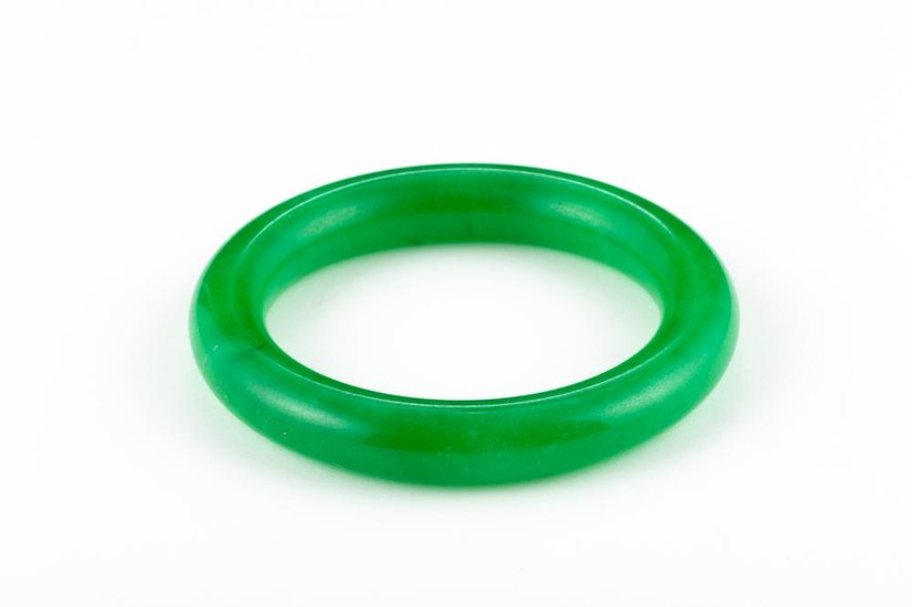 A FULL ROUND GREEN STONE BANGLE; dyed aventurine quartz, internal diam. 61mm.