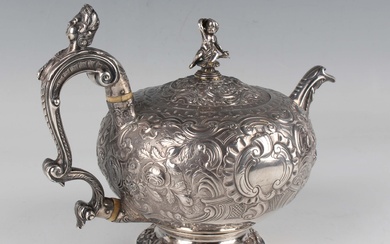 A George III silver teapot of compressed circular form with hinge lid and putto finial, the body cha