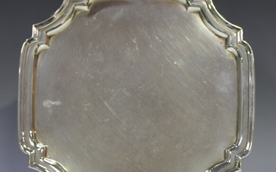 A George VI silver square salver with raised rim and shaped canted corners, on scroll legs, London 1