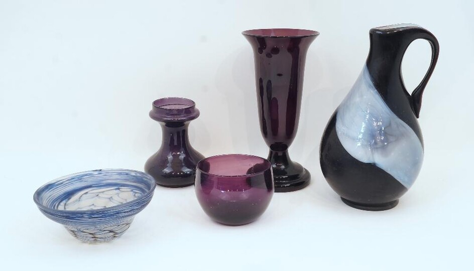 A Julia Donnelly studio glass bowl, with blue marblised design, signed and dated 1986, 16.5cm diameter; together with: a studio glass jug, unsigned, 28cm high; and three purple glass vases/bowl (5) ARR