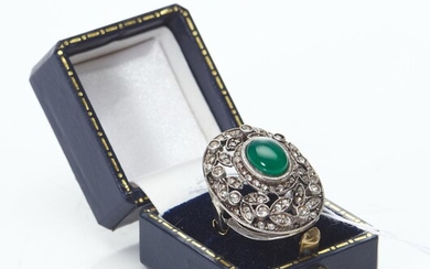 A LARGE DRESS RING IN SILVER FEATURING A CENTRAL CABOCHON CUT CHRYSOPRASE, WITHIN A DECORATIVE PIERCED SURROUND SET WITH COLOURLESS...