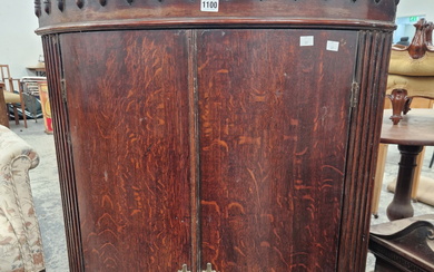 A LARGE GEORGE III OAK TWO DOOR BOW FRONT CORNER CABINET.