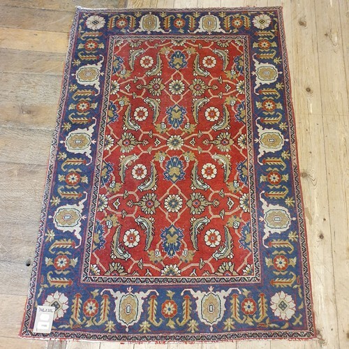 A Persian red ground rug, with main blue border, centre with...